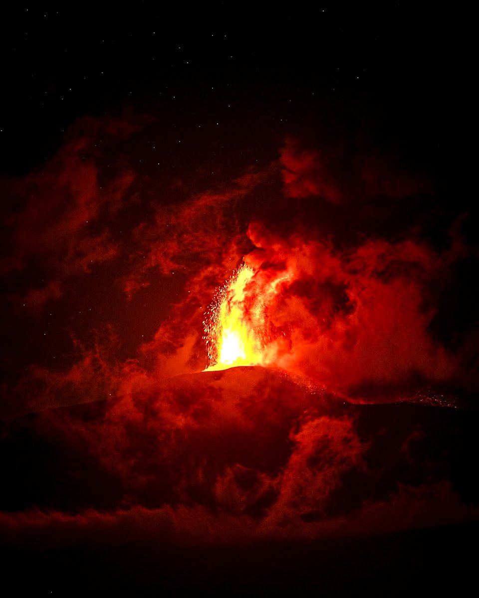 A volcano erupts lava in the night sky